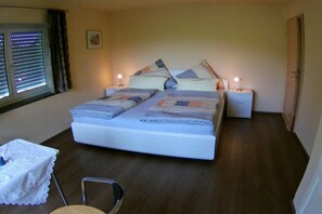 A bedroom with a bed, bedside tables, a chair, and a window with blinds. - Holiday home in Waltenhofen with barbecue (Waltenhofen)