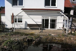 A house with a covered porch, a bench, and a small pond. - Holiday home in Waltenhofen with barbecue (Waltenhofen)