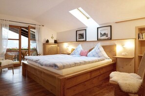 A cozy bedroom with a wooden bed, a skylight, a chair, and a bookshelf. - Holiday apartment with 1 bedroom (Bad Hindelang)