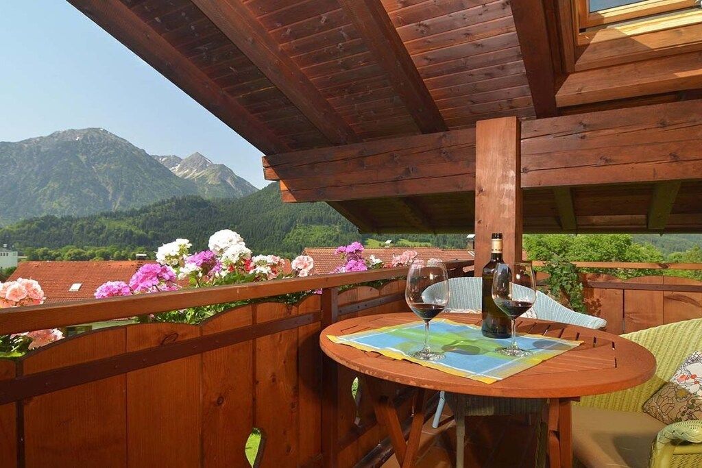 Une terrasse en bois avec une table dressée pour deux personnes, offrant une vue sur un paysage montagneux.