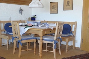 A dining area with a wooden table and chairs, a hanging light fixture, and framed artwork on the wall. - Country House Schwab - Holiday Apartment Fellhorn (Sonthofen)
