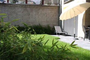 Eine Terrasse mit Stuhl, Tisch und großem Sonnenschirm.