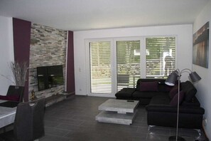 Ein Wohnzimmer mit Kamin aus Stein, einer Couch, einem Couchtisch und einer Stehlampe.