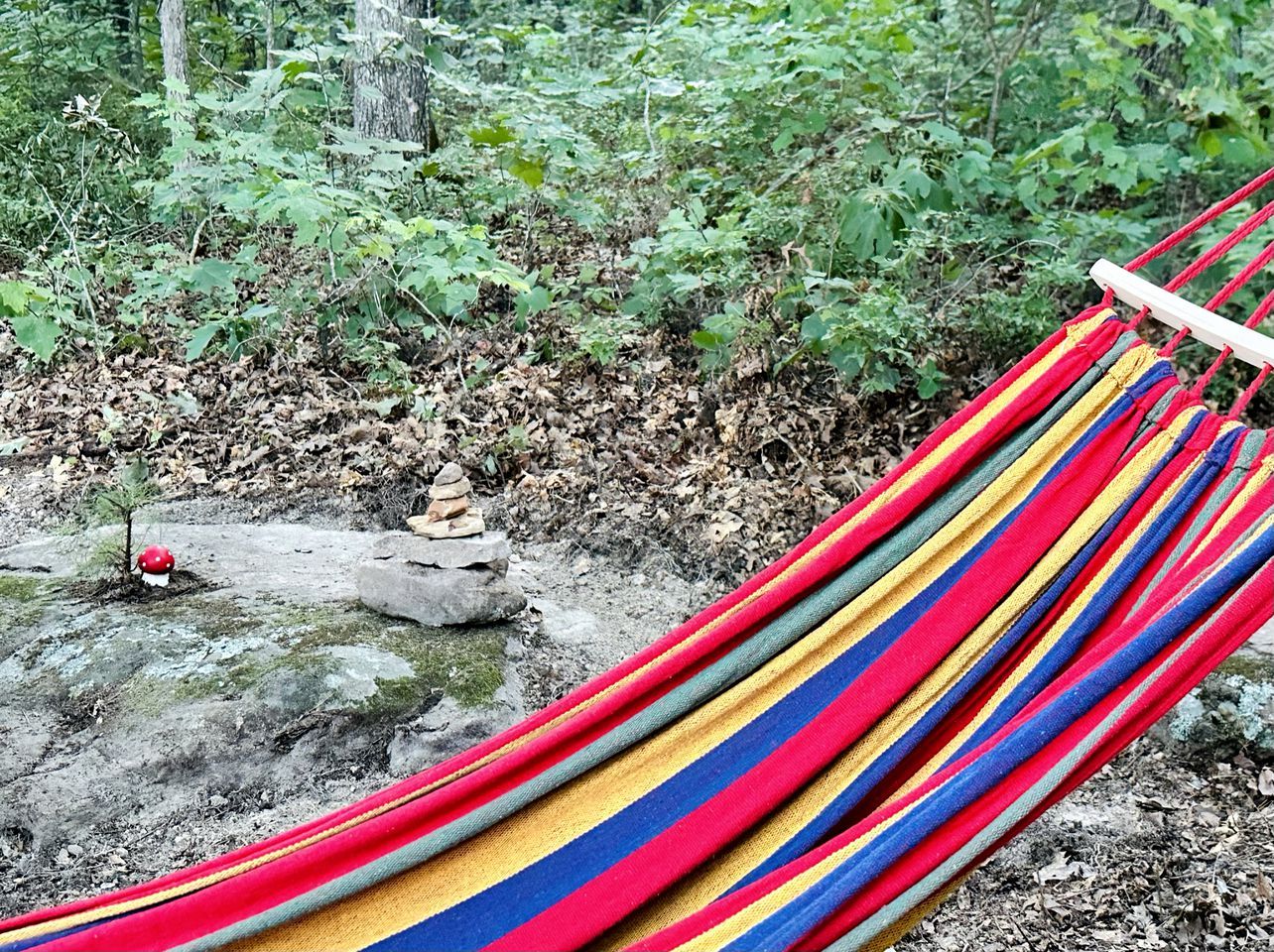 Een hangmat in een natuurlijke omgeving met een kleine rotsformatie en een paddenstoel.