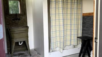 A bathroom with a wooden vanity, a shower curtain, and a black stool.
