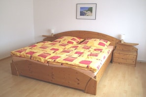 Een houten bed met hoofdbord, twee nachtkastjes en een aan de muur bevestigd schilderij.