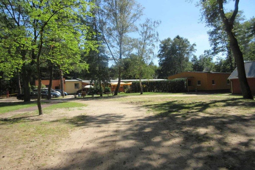 A residential area with a dirt driveway, a yellow building, and trees.