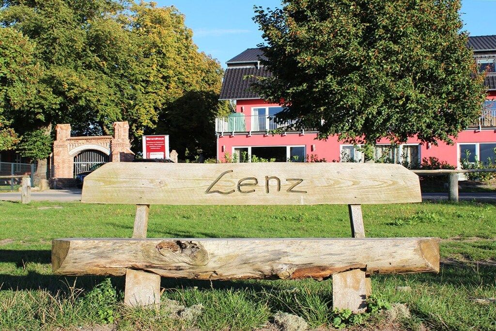 Un banc en bois portant l’inscription « Lenz », situé dans un parc.