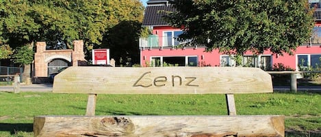 Eine Holzbank mit der Aufschrift 'Lenz' in einer Parkanlage.