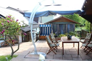 Un espace extérieur aménagé avec une table et des chaises, un coin salon abrité et un petit abri de jardin.