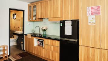 A modern kitchen with wooden cabinets, a black refrigerator, and a sign indicating no gambling, drugs, or weapons.