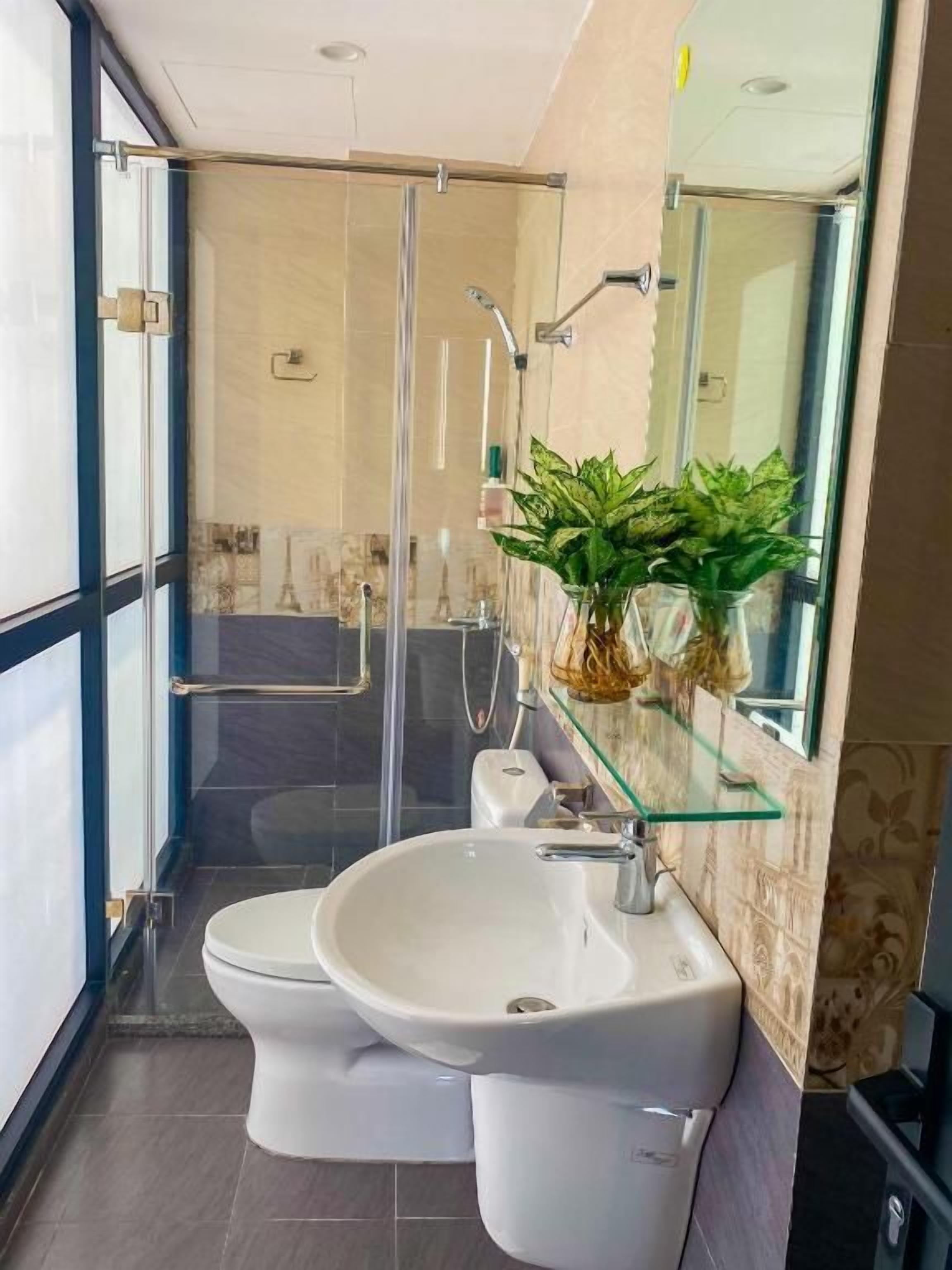 Ein modernes Badezimmer mit einer Glasdusche, einem weißen Waschbecken und einer Toilette.