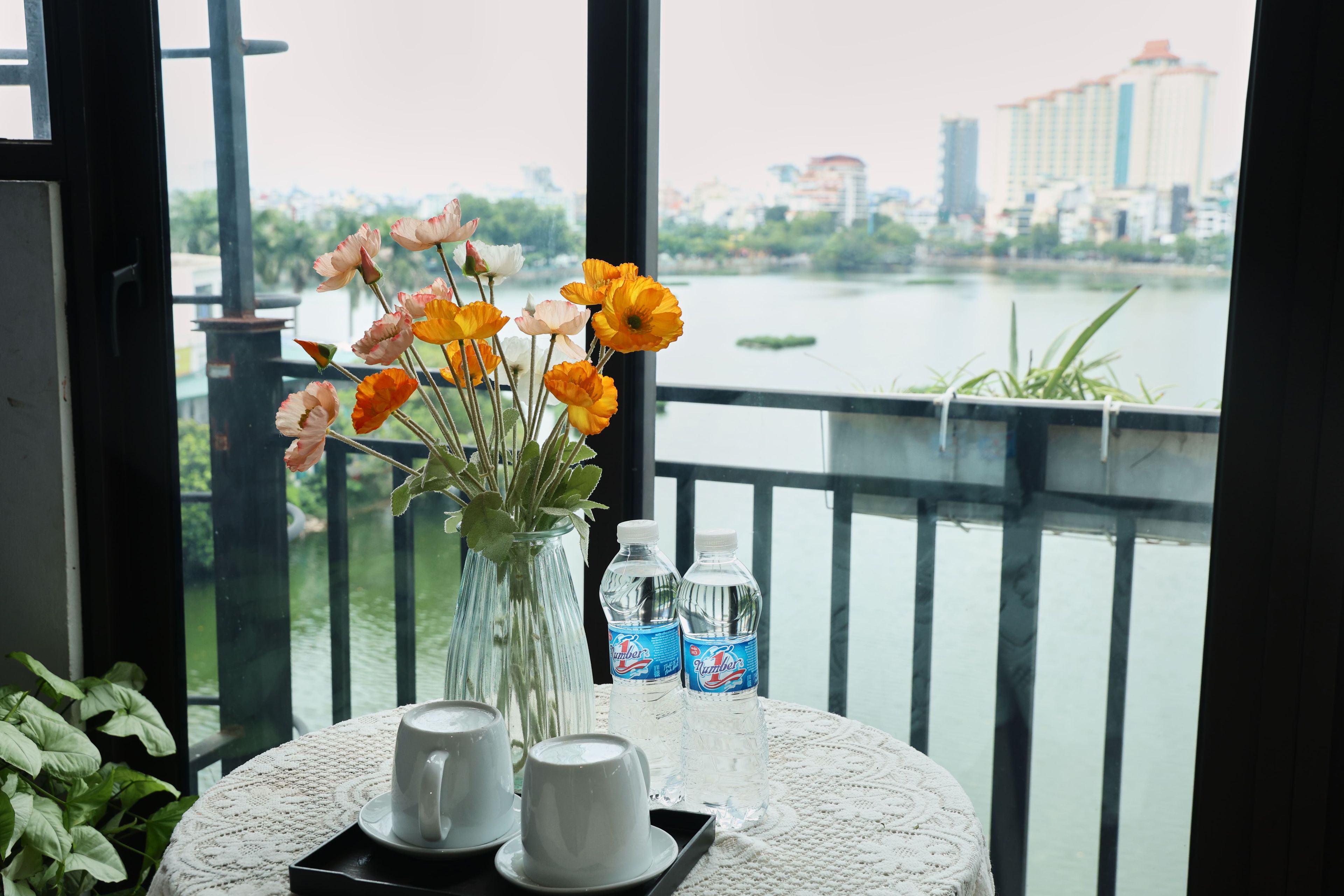 Ein Tisch mit Blumen in einer Vase, zwei Tassen und zwei Wasserflaschen.