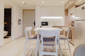 Een moderne keuken met witte kastjes, een ingebouwde magnetron en een koelkast van roestvrij staal.
