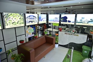 Zona de recepción con un sofá marrón, mostrador de recepción y múltiples monitores mostrando imágenes de puntos de referencia.