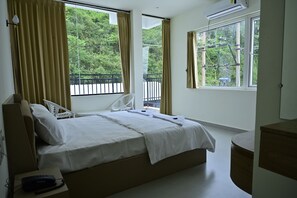 Ein Hotelzimmer mit einem Bett, einem Sessel, einem kleinen Tisch und Blick auf Grünflächen.