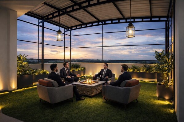 Eine Dachterrasse mit Feuerstelle, Sitzgelegenheiten und Blick auf die Stadtlandschaft.