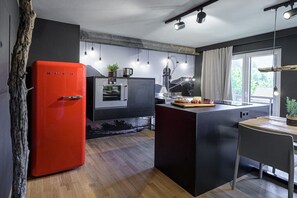 Eine moderne Küche mit einem roten Kühlschrank, einem Backofen, einer Spüle und einem Essbereich mit Tisch und Stühlen.