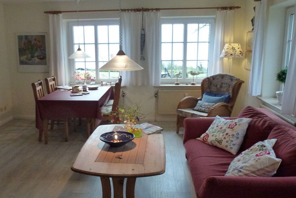 Un salon chaleureux avec une table en bois, un canapé rouge et un coin repas comprenant des chaises et une table.