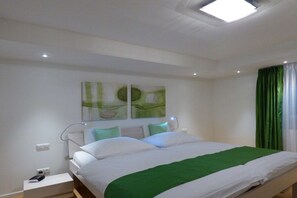 A modern bedroom with a bed, bedside tables, and a ceiling light. - Holiday apartment with 3 bedrooms (Garmisch-Partenkirchen)