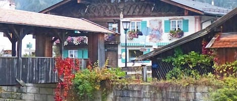 Ein traditionelles Chalet mit Holzfassade, einer Steinmauer im Vordergrund und einem Berg im Hintergrund.