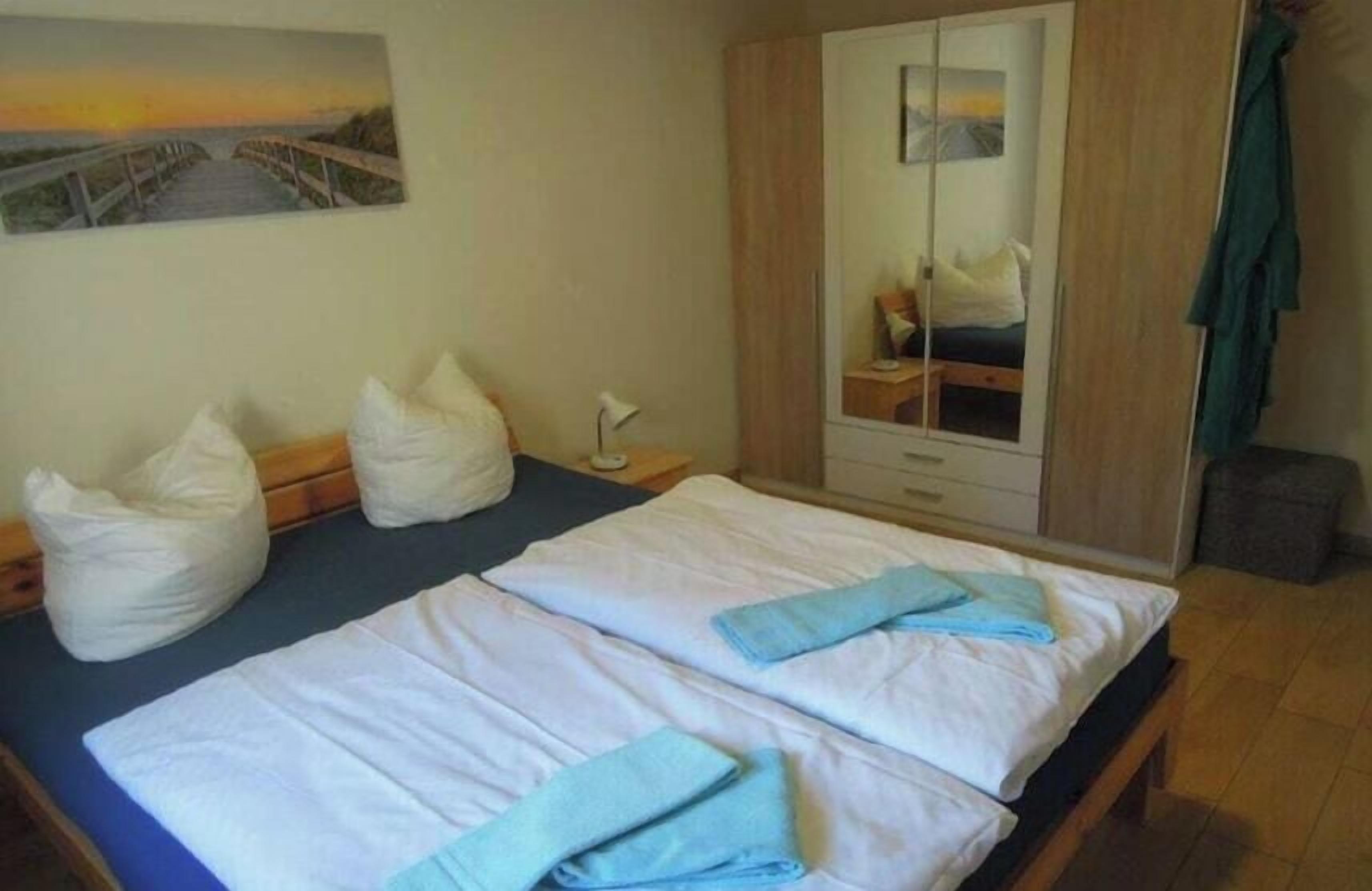 Une chambre avec deux lits, une armoire et un tableau au mur.