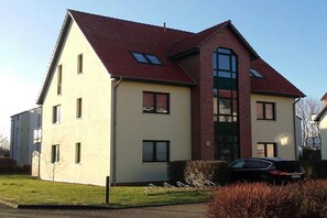 A two-story residential building with a red-tiled roof, multiple windows, and a car parked in the driveway. - Kühlungsborn West Beach (Kühlungsborn)