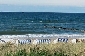 A beach with striped beach umbrellas and a wooden jetty extending into the sea. - Kühlungsborn West Beach (Kühlungsborn)