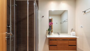 Un bagno moderno con cabina doccia in vetro, mobile bagno in legno e uno specchio grande.