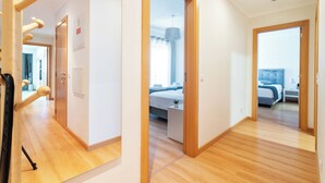 Una camera d'albergo con pavimento in legno, un letto con testiera blu, un comodino e una piccola pianta in vaso.