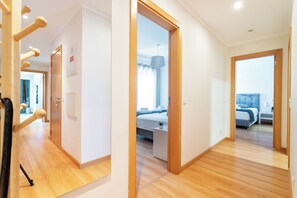 Een hotelkamer met een houten vloer, een bed met een blauw hoofdeinde, een nachtkastje en een kleine potplant.