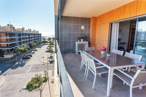A balcony with a dining table and chairs, a view of the street, and a building in the background. - Privilege 2-Bedroom Apartment with Rooftop Pool Terrace, Village Marina - Olhão (Olhão)