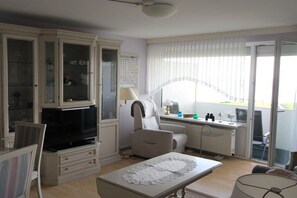 Una sala de estar con televisión, una mesa de comedor, un sofá y una ventana con persianas.