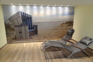 Una habitación con un mural de playa, dos sillones de descanso y una mesita.