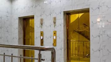 Un ascensor moderno con baldosas de mármol en las paredes y detalles dorados en el interior.