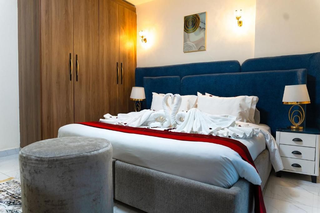 Een hotelkamer met een bed, nachtkastjes, een kledingkast en een rond poef.