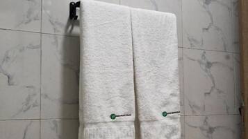 Un baño con azulejos de mármol blanco y dos toallas colgadas en un perchero.