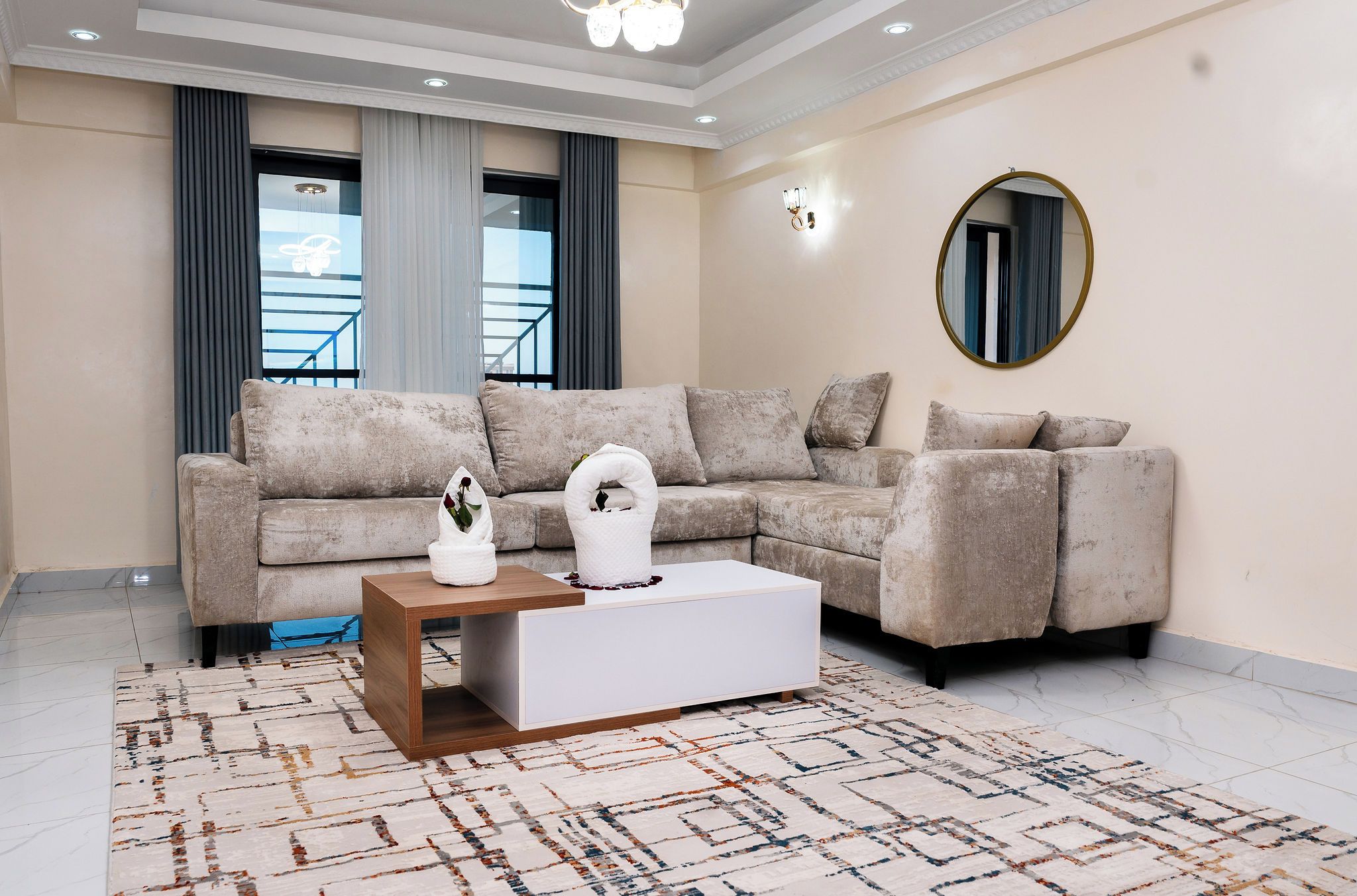 Una sala de estar con un sofá modular, una mesa de centro y un espejo grande en la pared.