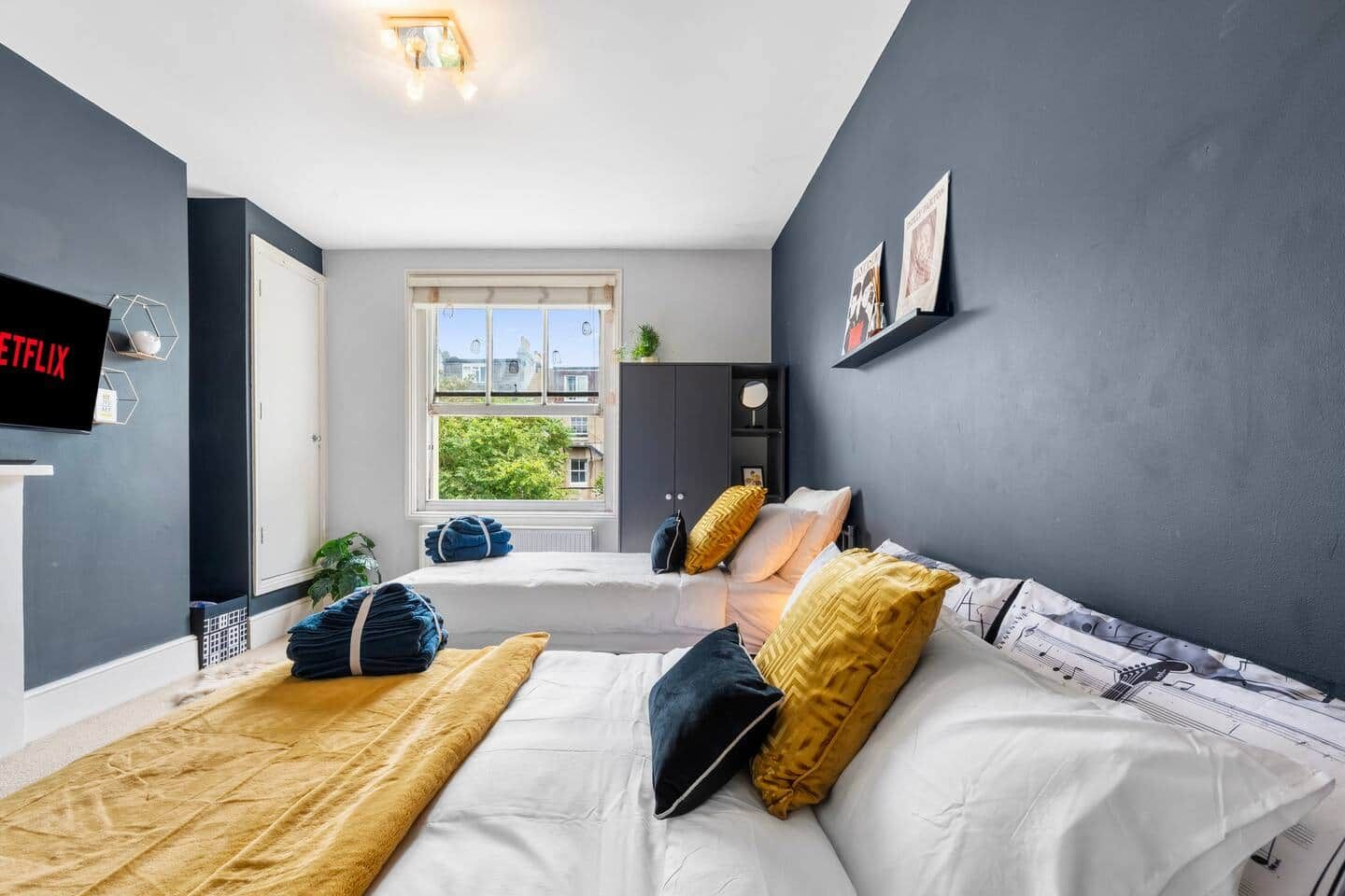 A modern bedroom with a bed, a TV, a window, and a door.