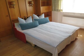 A bedroom with a bed, wooden wardrobe, and a window with curtains. - 1 in the Sonnenbichl house (Walchensee)