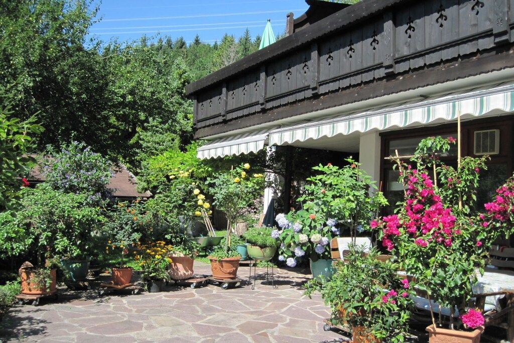 Ein traditionelles Gebäude mit einem pflastergelegtem Innenhof, umgeben von verschiedenen Blumentöpfen und Blumen.