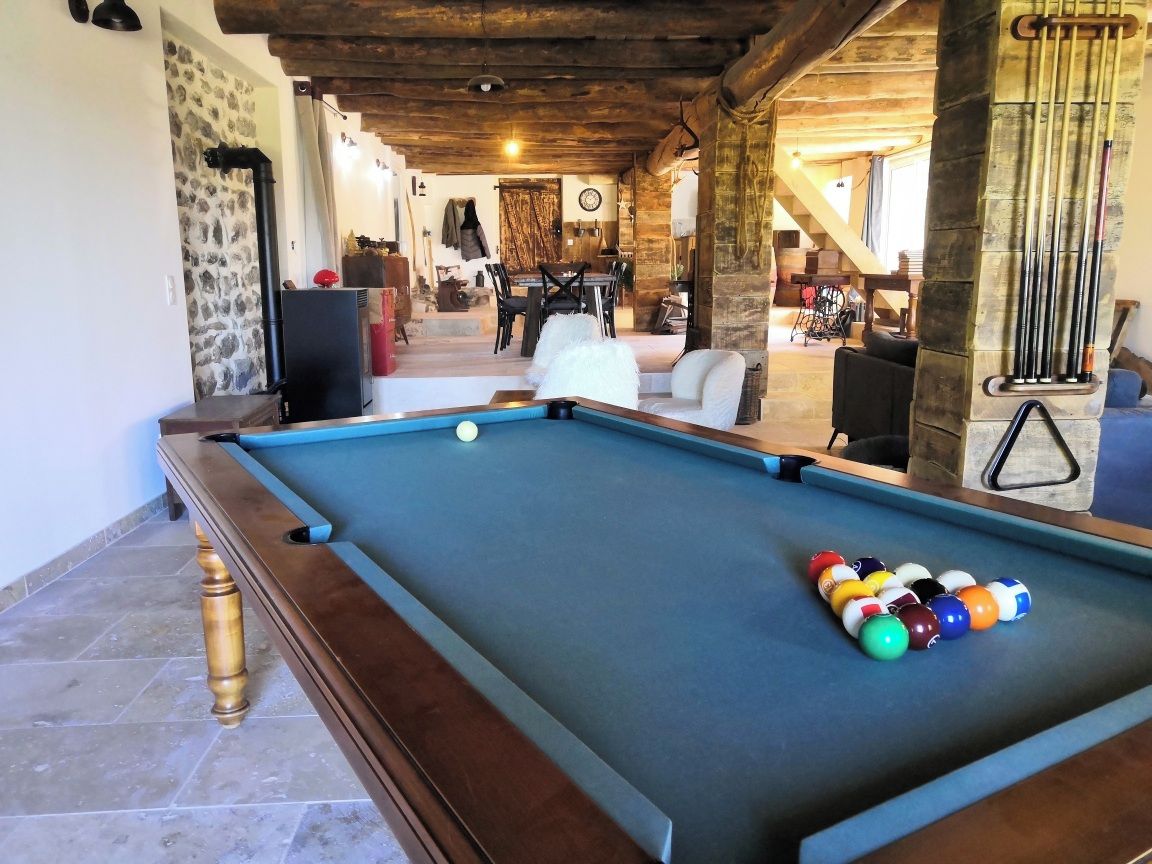 A pool table with balls, a stone wall, and a staircase leading to a dining area.