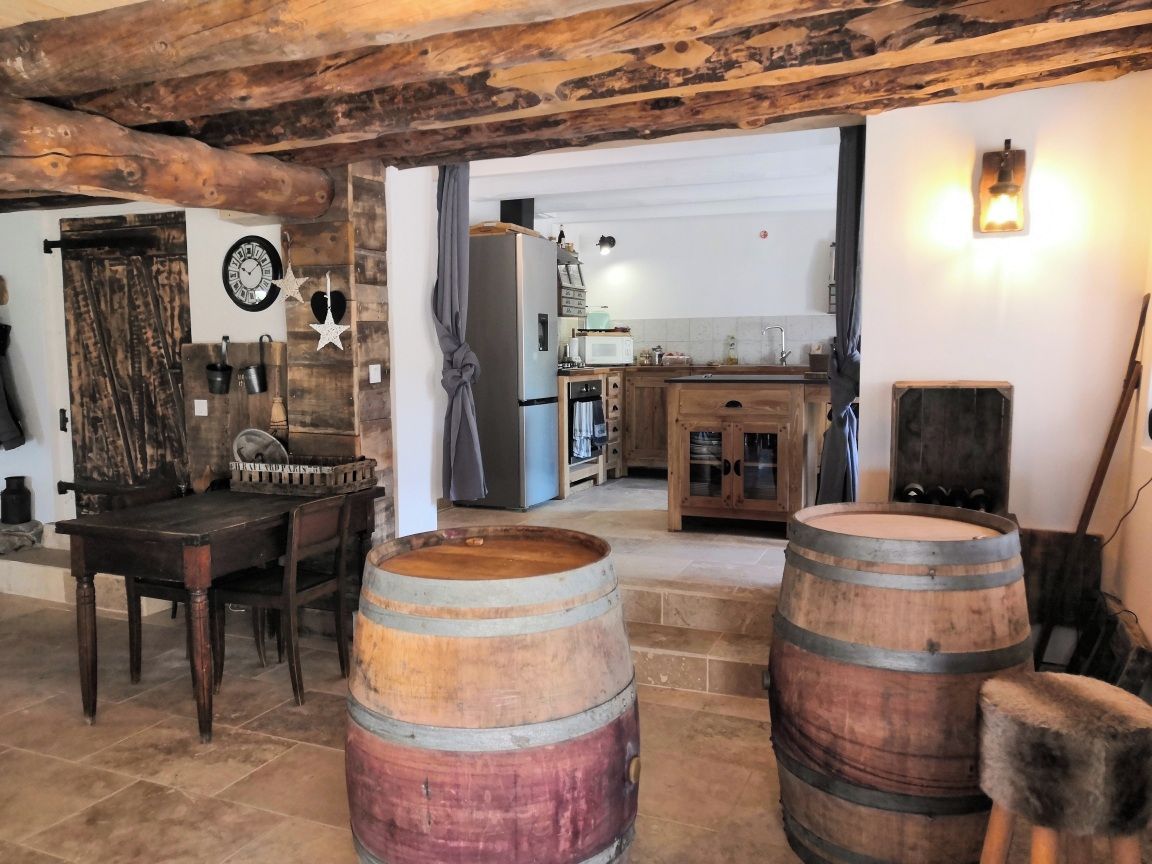 Een rustiek interieur met houten vaten, een eettafel en een keukenhoek.