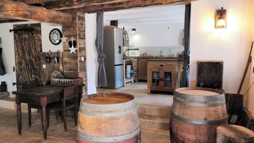 Een rustiek interieur met houten vaten, een eettafel en een keukenhoek.