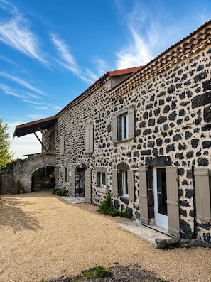A stone building with a gravel driveway and a wooden archway.