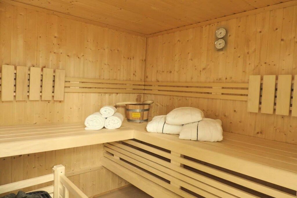 Un sauna avec des murs en bois, des bancs, des serviettes et un seau.