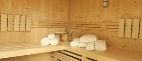 Ein Saunaraum mit Holzwänden, Bänken, Handtüchern und einem Eimer.