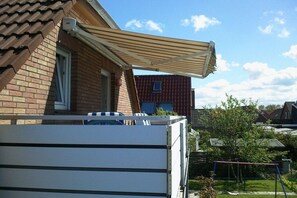 A residential area with a brick house, a covered patio, and a swing set in the yard. - Holiday apartment with 2 bedrooms (Norden)