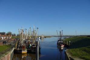 A canal with boats docked on both sides, a clear sky, and a grassy embankment. - Holiday apartment with 1 bedroom (Osteel)