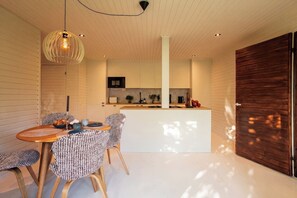 A modern kitchen with white cabinetry, a wooden dining table with patterned chairs, and a pendant light. - Stay North - Apple House (Kangasala)